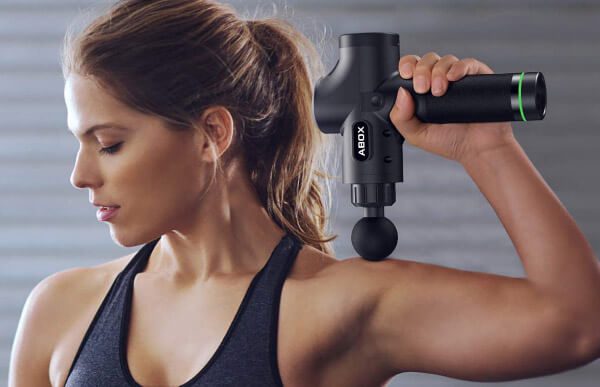femme qui se masse avec un pistolet de massage musculaire