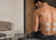 Homme utilisant un électrostimulateur pour le dos avec des électrodes placées sur les muscles lombaires